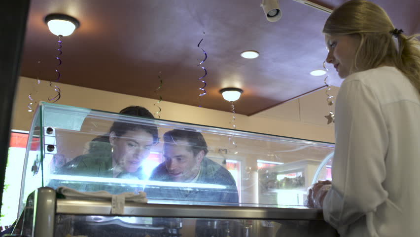 Medium shot of a couple tasting ice cream in a pastry shop