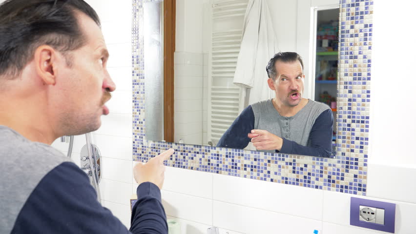 Man looking himself in mirror angry acting like bad guy Shutterstock HD Vid...