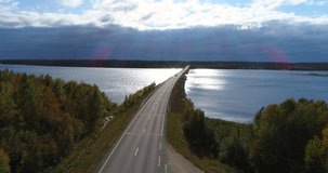 Autumn color bridge, Cinema 4k aerial decreasing view of cars driving over a bridge on route e75 full of different fall colors, near inari, on a sunny autumn day, in Lapland, Finland