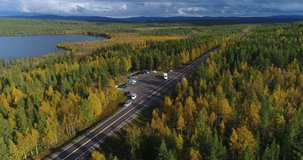 Autumn lake, Cinema 4k aerial view around a parking lot full of Rv and cars, revealing colorful autumn trees, sarkijarvi lake and fjeld mountains, near pallas-yllas national park, Lapland, Finland