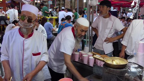 LANZHOU, CHINA - JULY 2017 - Muslim men working as cook preparing traditional Chinese street food in Lanzhou, Gansu province, China, Asia. Market with stalls and shops selling Asian food