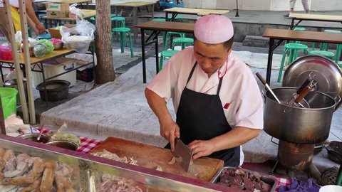 LANZHOU, CHINA - JULY 2017 - Man working as cook preparing traditional Chinese street food in Lanzhou, Gansu province, China, Asia. Market with stalls and shops selling Asian food. People at work