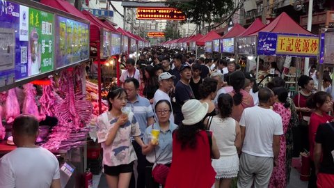 LANZHOU, CHINA - JULY 2017 - Zhengning Road, night market, food street in Lanzhou, Gansu province, China, Asia. Fair with stalls and shops selling Asian food. People buying snacks and dinner