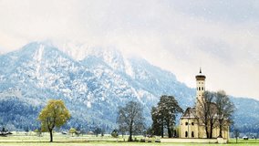 The Church St. Coloman while snowing. The winter landscape, Schwangau, Germany. Snowy mountains in background