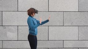 Woman using finger to touch on imaginary panel viewing on VR device outdoors. Augmented virtual reality concept.
