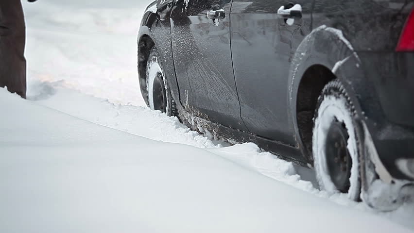 The car stalled on a snowy road and people kicking him out of a snowdrift