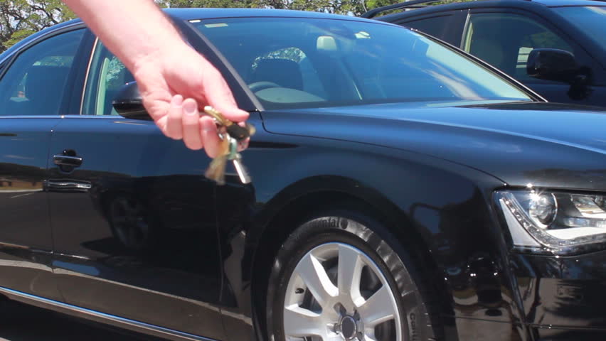 Waving Car keys in fron of brand new luxury car