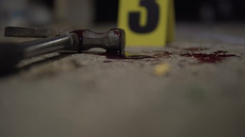 Hammer bloody murder weapon detail. Part of a crime scene site at night collection. Forensic  police scientists working, looking for clues and evidence. Blood splatter analysis. In 4K, interior.