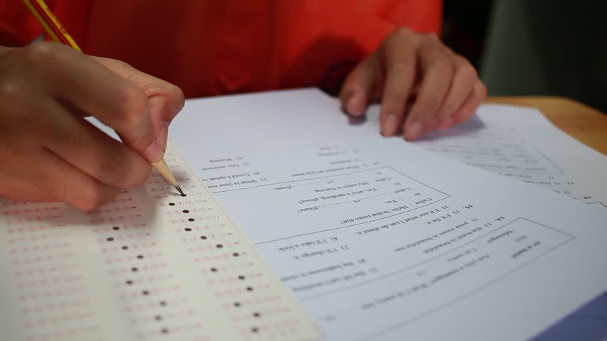 Students hand testing doing examination with pen drawing selected choice on answer sheets in school exams, blur pupils college background. Education system tests concept.Students hand testing exam Royalty-Free Stock Footage #32883589