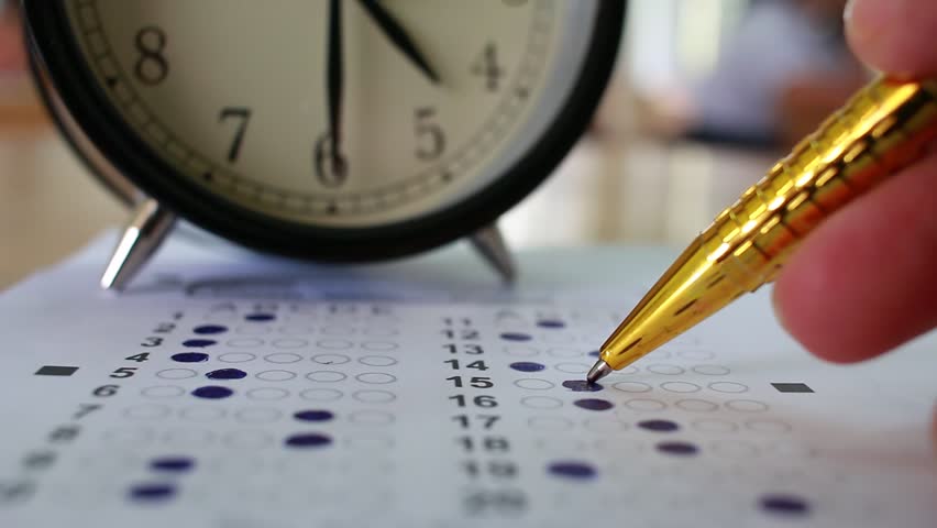 Students taking exams writing on optical form of standardized exam near Alarm clock with holding yellow pen for final examination in secondary school, college university classroom, Education concept Royalty-Free Stock Footage #32883598