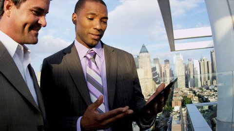 African American and Caucasian male smart business managers planning funds on touch screen rooftop overlooking Manhattan shot on RED EPIC