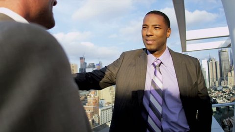 Handshake of multi ethnic male and female executive managers talking business strategy using tablet on rooftop overlooking Manhattan shot on RED EPIC