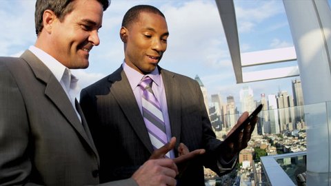 Multi ethnic male successful executive managers working on portfolio online tablet on rooftop overlooking Manhattan shot on RED EPIC