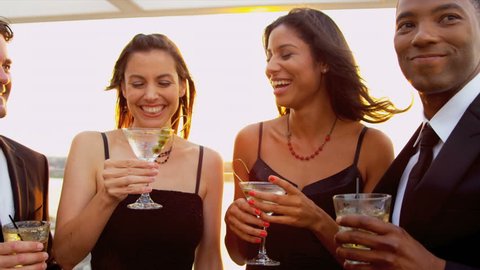 Two happy diverse women drinking cocktails with handsome men at luxury sunset party dressed in black shot on RED EPIC