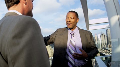 African American and Caucasian male business managers have information meeting on rooftop overlooking New York shot on RED EPIC