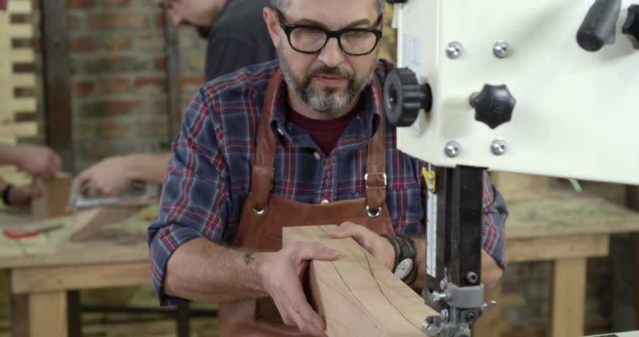 Middle aged cabinet maker creates a cabrioli table leg using professional bandsaw. He has a restoration shop, most probably a family business/Mature Cabinet Maker Creates a Cabrioli Leg Using Bandsaw, a Business & Finance Video by Dzhafarov Eduard