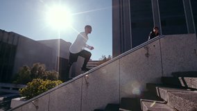 Free runners in action outdoors in city. Two young men doing parkour tricking and freerunning in the city. Jumping from an obstacle and running. 