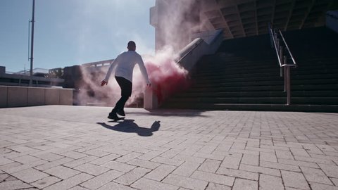 Free runners with smoke grenades performing parkour in urban space. People doing parkour tricking and freerunning in the city. 