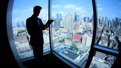 Silhouette young male Caucasian finance manager working on touch screen in modern Manhattan office
