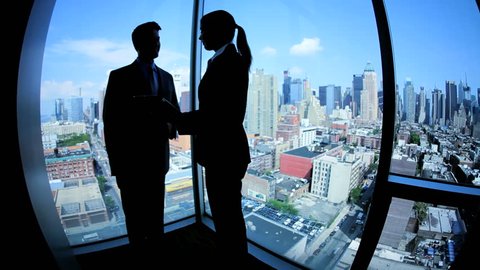 Silhouette Caucasian male and female successful managers planning investment banking using tablet in modern workplace in Manhattan