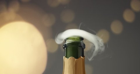 Close up slowmotion video of man's hands opening a bottle of champagne on gray background with lights and flares