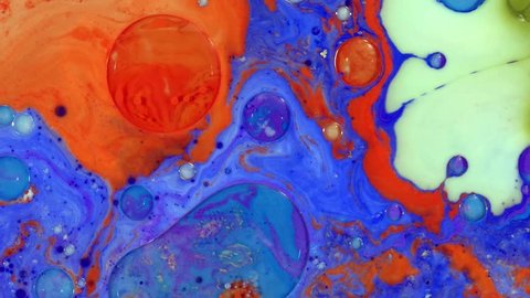 Colorful paint drops mixing in water. Ink swirling underwater. Liquid paint colorful bubbles patterns of moving surface,  river of liquid, movement of colorful paint.  