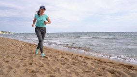Athletic woman running along the beach. Video at different speeds - normal and slow