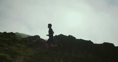 Athletic man trail running in foggy mountains