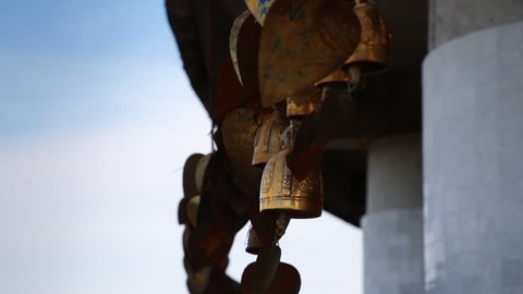 Close up of golden wishing bells and metal leaves with hand-written text are swaying in the wind, Phuket Big Buddha temple in Thailand.