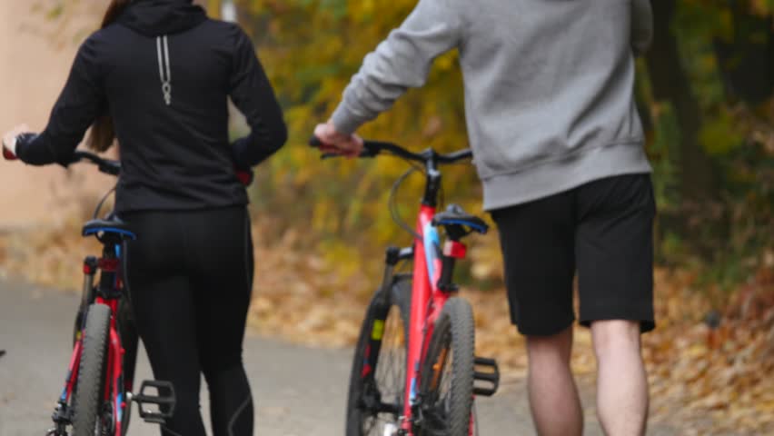 A woman and a man riding a bike an autumn day