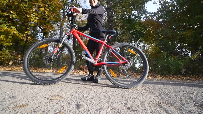 Close up shot of young woman on a bicycle in the autumn park. slow motion