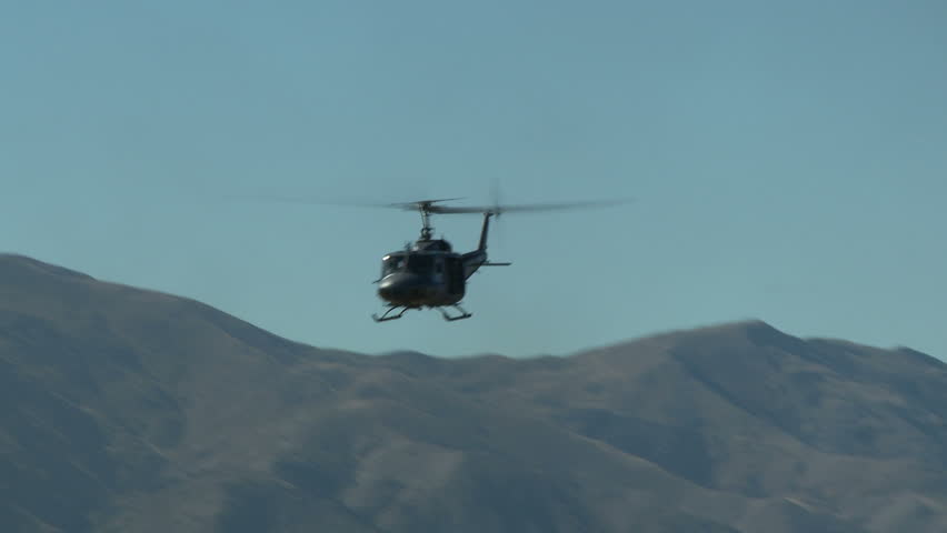 Pan right to left of an Iroquois helicopter in a slow low level close flight