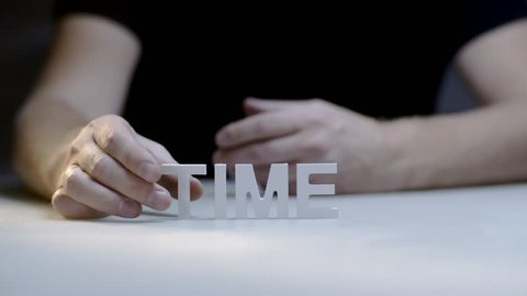 Male hands composition and breaking word time by white letters on gray background. Man manages time. Power time over life