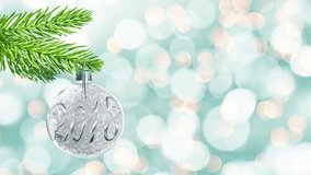 Seamless loop - 2018 on a silver christmas ball hanging from a branch, holiday lights background, video HD