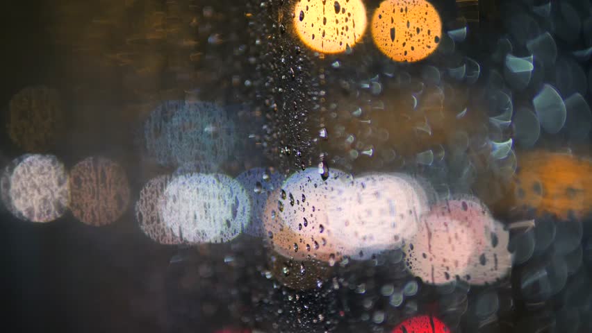 Rain Water Drops on Bus Window Glass in Rainy Day with Blurred Night City Traffic as Background. 4K.