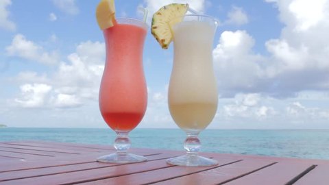 Tropical winter vacation with Pina Colada cocktail and passion fruit drink on the table with Indian ocean view. Ocean view with tropical cocktails. Close up of two glasses with cold refreshing drink. 