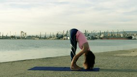 Woman performing Yoga exercises on the beach - 4K video