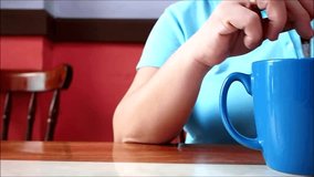 Video of a woman stirring coffee in a mug