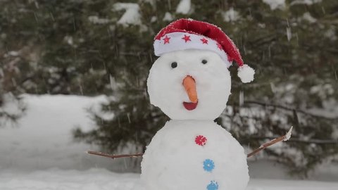 Fun festive snowman standing in the snow is snowing
