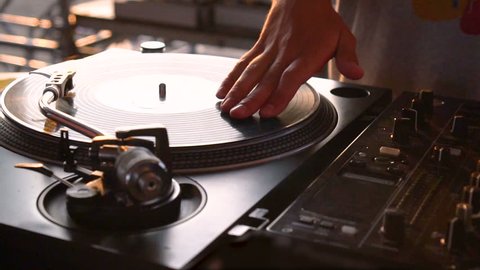 Mix and scratch, hands of a DJ on vinyl and mixer knobs. Slow motion 120 fps. Shooting with gimbal. Sunset.
