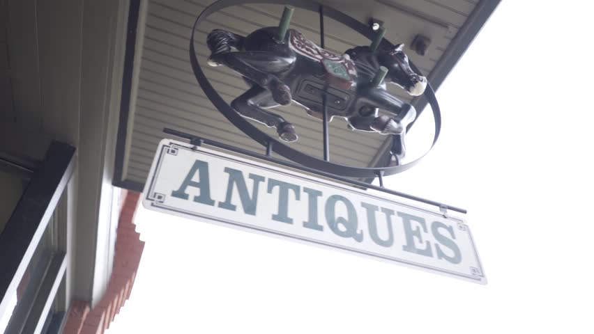 Steadicam shot of “Antiques” store sign with child’s rocking