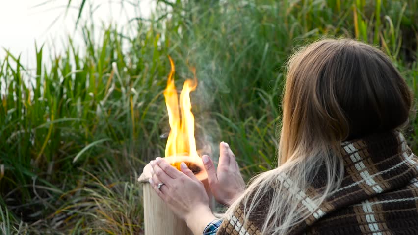 Beautiful girl warm hands near the fire