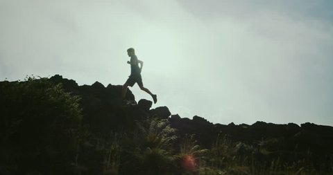 Athletic man trail running in foggy mountains
