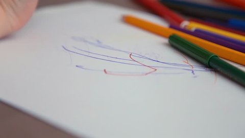 little boy draws with colored pencils