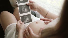 Couple looking at ultrasound scan of baby on sofa - Powered by Shutterstock - Get 15% off with code: PIKWIZARD15