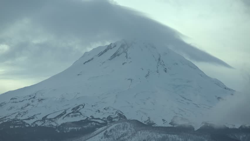 Mt. Hood in winter snow covered mountain and forest at dusk sunset telephoto close summit blowing snow
