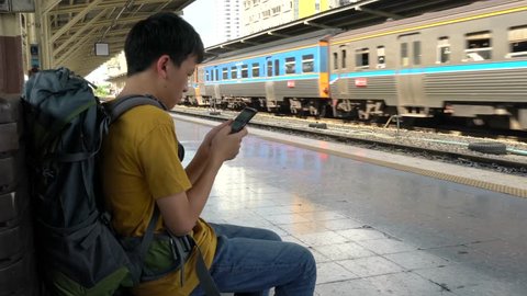 asian boy wait for a train by playing smartphone