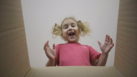 A little girl looks in the box, is surprised and happy to receive a surprise. The child opened a box with a gift.Slow Motion