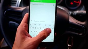 Video of a hand typing on a smartphone while inside a car.
