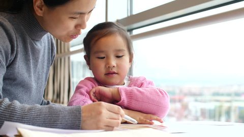asian little girl doing homework with her mother help in slow motion